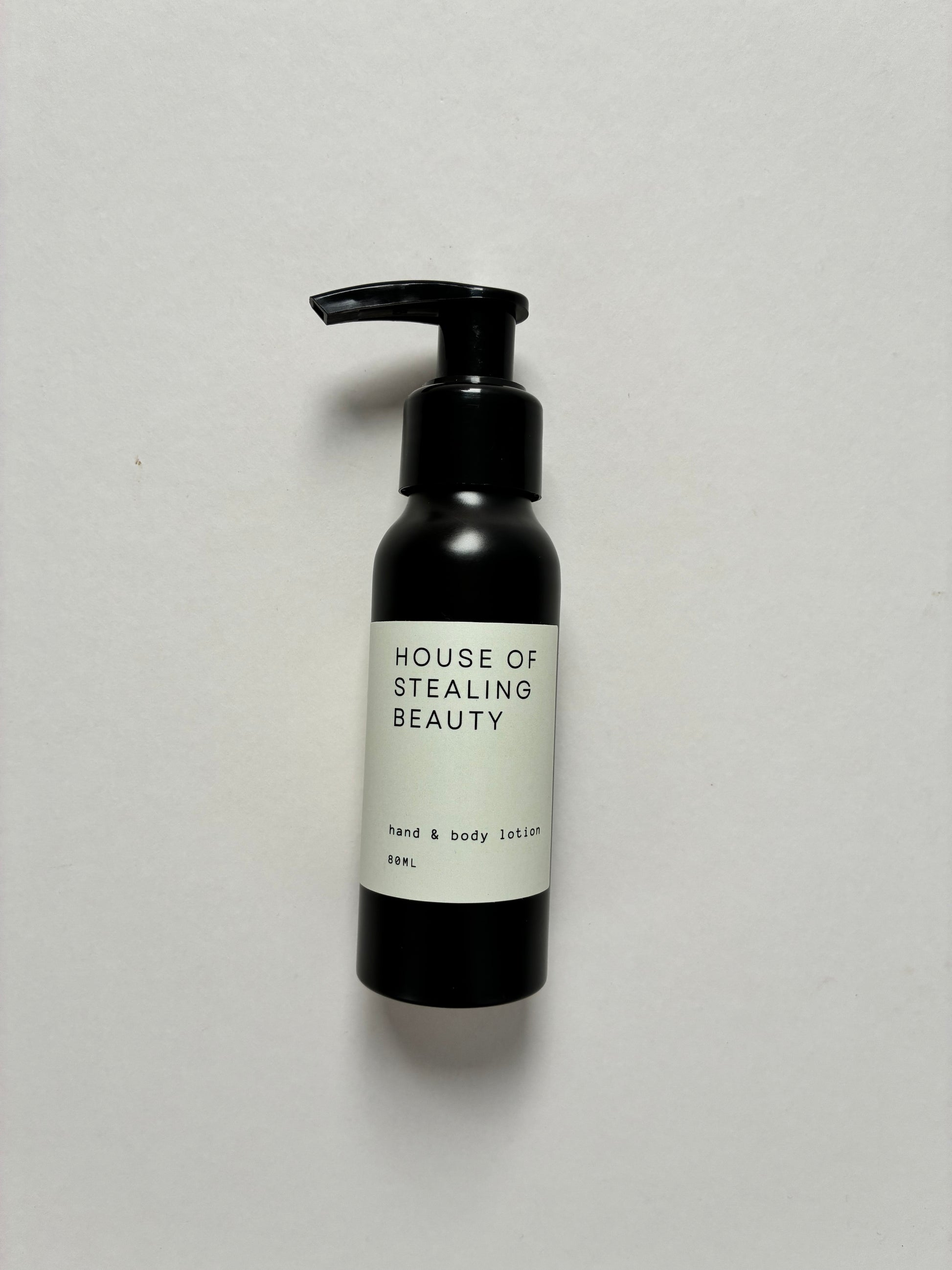 A black pump bottle labeled 'HOUSE OF STEALING BEAUTY hand & body lotion' on a light background.